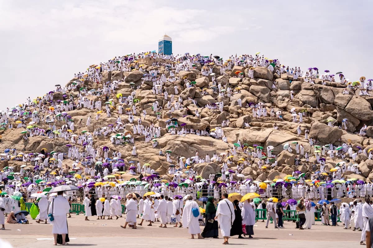 Pilgrims gathered on Mount Arafat during Hajj, with umbrellas for shade