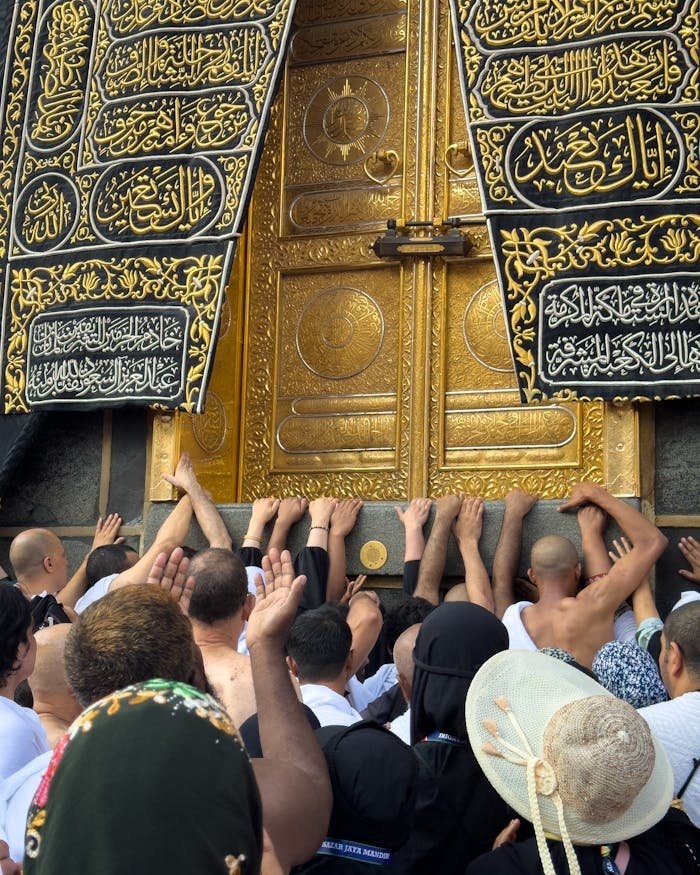 Pilgrims reaching for the golden Kaaba door, a sacred moment during Hajj in Mecca.